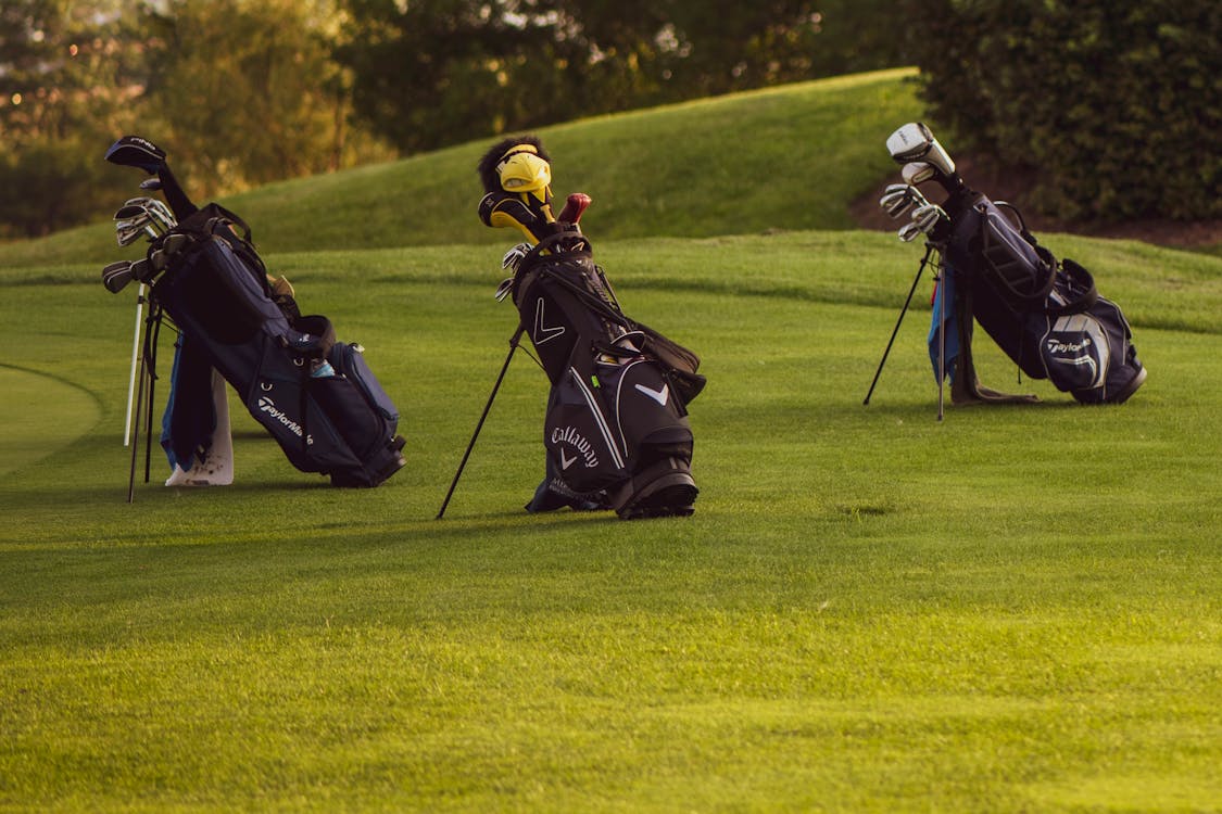 Trois sacs de golf alignés sur un parcours prêts pour une partie